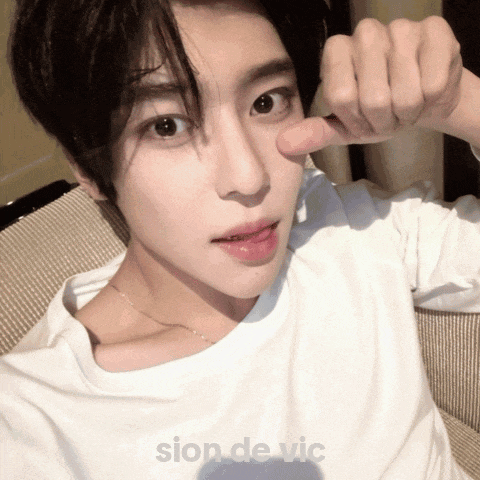 a young man in a white shirt is making a funny face with his fingers