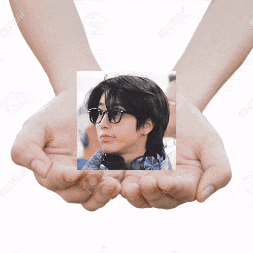 a pair of hands holding a picture of a woman wearing sunglasses