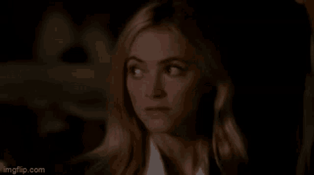 a woman is making a funny face with her eyes closed in a dark room .