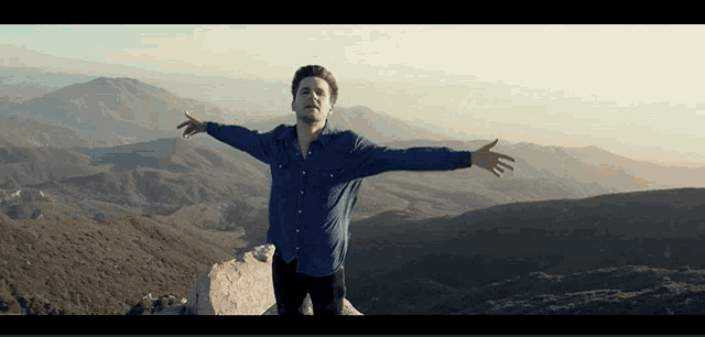 a man with his arms outstretched stands on top of a mountain