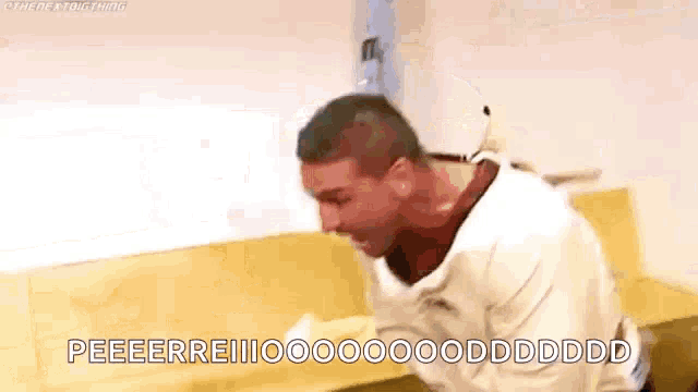 a man in a strait jacket is sitting on a couch and screaming .