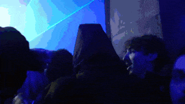 a man in a hooded jacket stands in a dark room