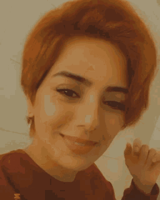 a close up of a woman 's face with red hair and a red shirt .