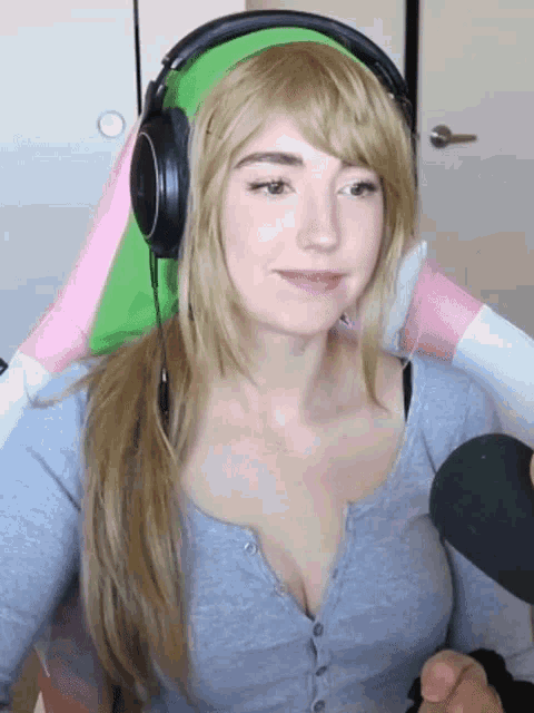 a woman wearing headphones and a gray shirt is smiling