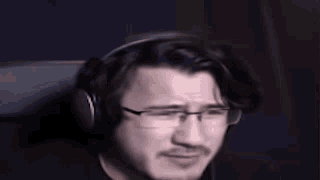 a man wearing headphones and glasses is sitting in a dark room .
