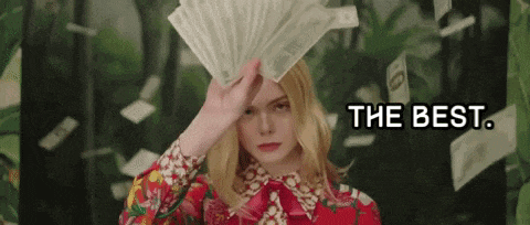 a woman in a red dress is holding a fan of money in her hand .
