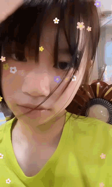 a girl with flowers on her face is wearing a yellow shirt