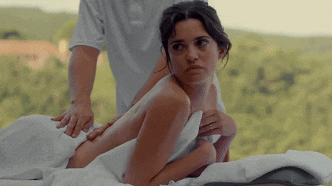 a woman is laying on a massage table with a man behind her