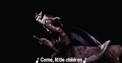 a woman in a purple dress is singing a song while holding a broom .