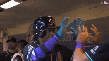 a baseball player wearing a black helmet and purple sleeves is hugging another player