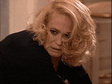 a woman with blonde hair is wearing a black shirt and looking at the camera