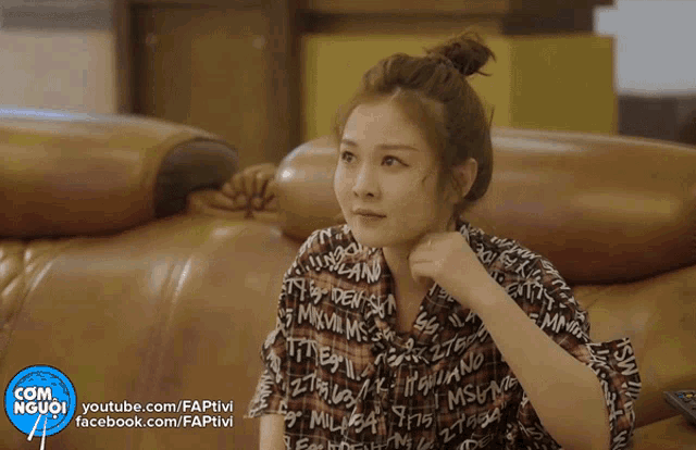 a woman in a plaid shirt is sitting on a couch next to a com người youtube channel