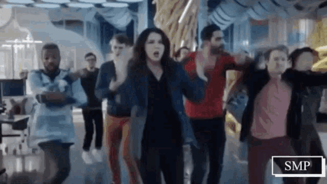 a group of people are dancing in a room with a sign that says smp on it