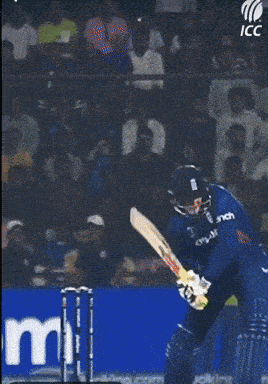 a cricket player in a blue uniform is swinging a bat at a ball
