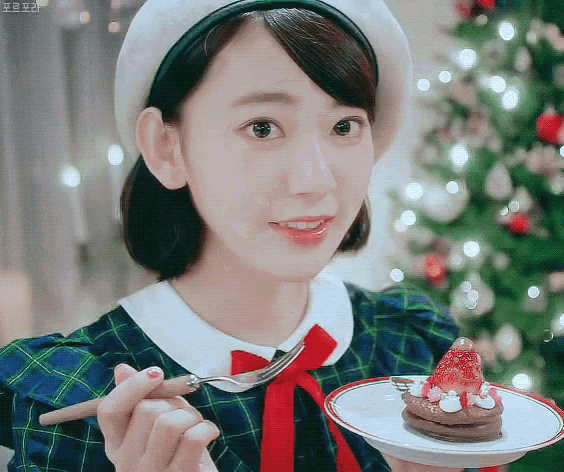a girl in a plaid dress is holding a plate with a dessert on it