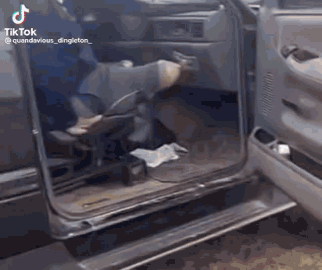 a man is sitting in the back seat of a truck with his legs crossed .
