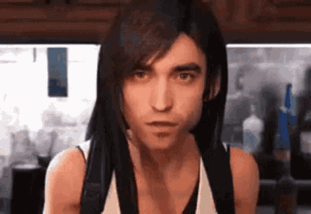 a man with long hair is wearing a white tank top and a backpack .