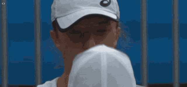 a woman wearing a white asics hat looks down