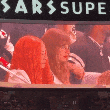 a couple of women sitting in front of a sign that says sarssupe