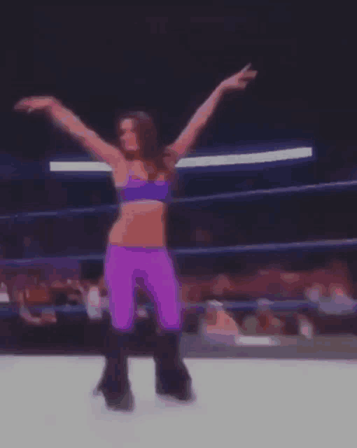 a woman in purple pants and a blue top is dancing on a stage