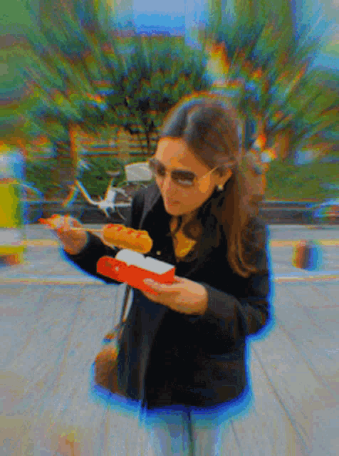 a woman is eating a hot dog from a box