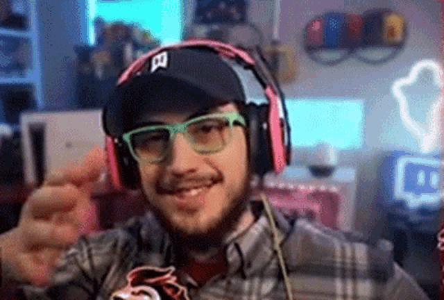 a man wearing headphones and glasses is giving a thumbs up sign .