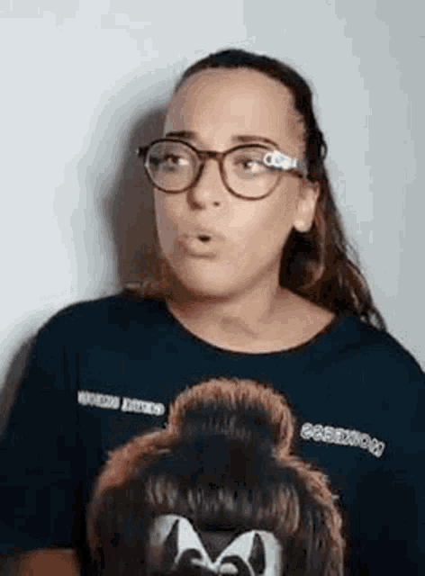 a woman wearing glasses and a t-shirt with a picture of a monkey on it is making a face .