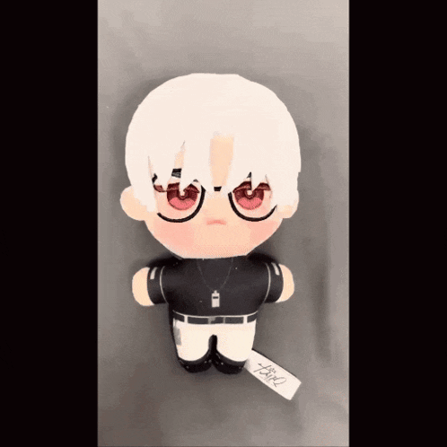 a stuffed doll with white hair and red eyes has a tag that says ' tsgk ' on it