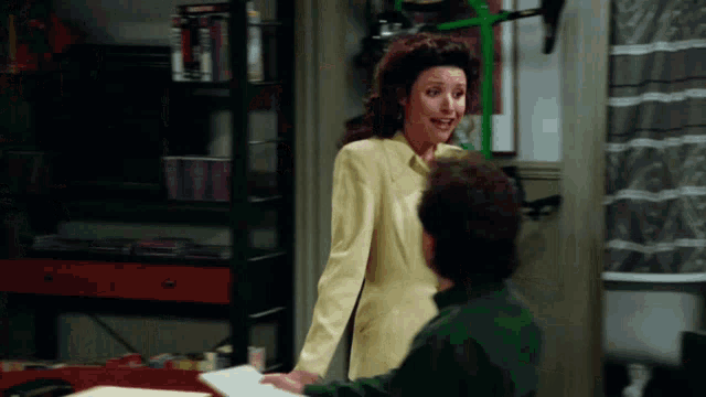 a woman in a yellow jacket is talking to a man