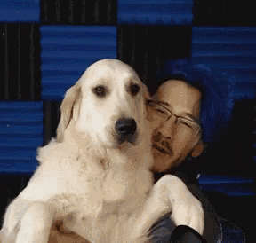 a man with blue hair is holding a small white dog .