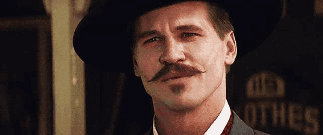 a man with a mustache is wearing a hat and suit