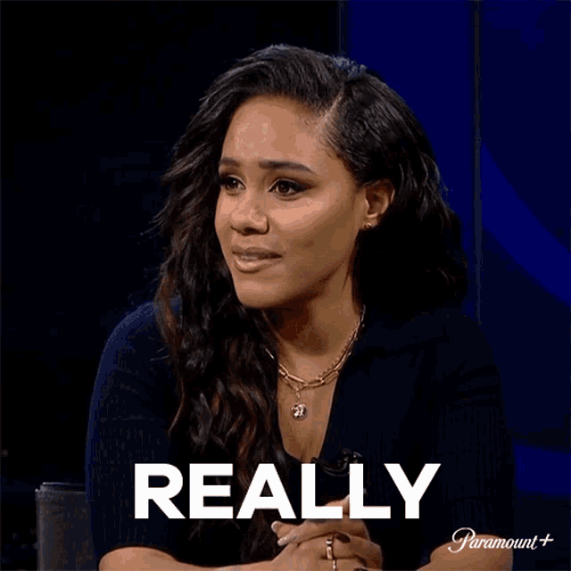 a woman is sitting in front of a screen that says really
