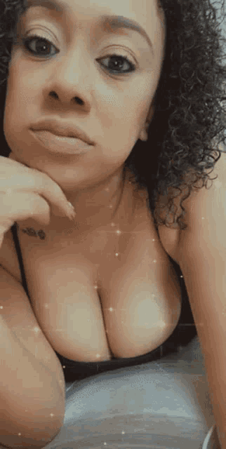 a woman with a tattoo on her arm is taking a selfie with her breasts visible .