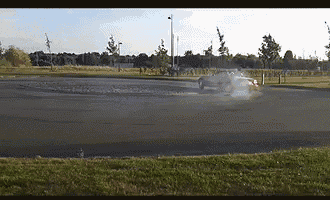 a car is drifting on a road with grass in the foreground