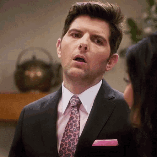 a man in a suit with a pink tie and a pink pocket square