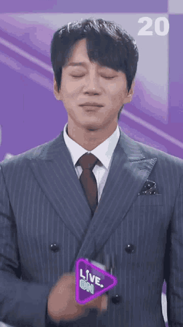 a man in a suit and tie has a live on sign on his chest