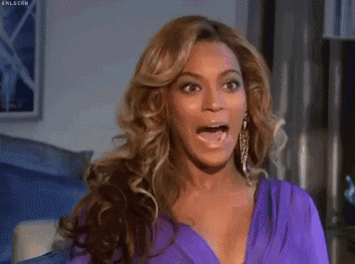 a woman wearing a purple shirt and earrings is making a funny face .