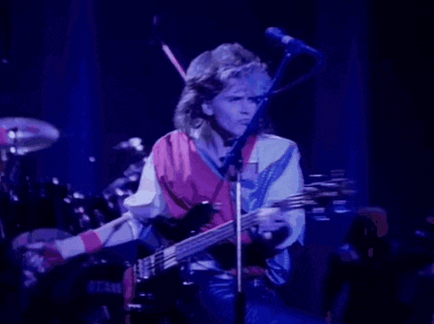 a man is playing a guitar and singing into a microphone while standing on a stage .