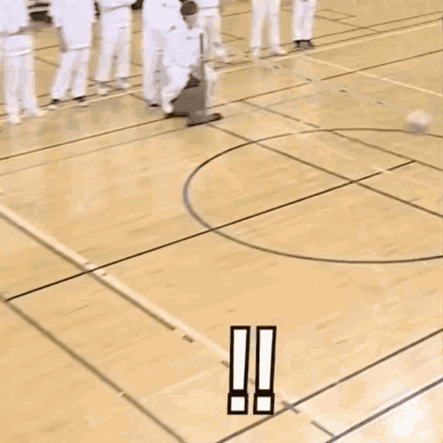 a person is laying on the floor of a basketball court while another person is playing basketball .