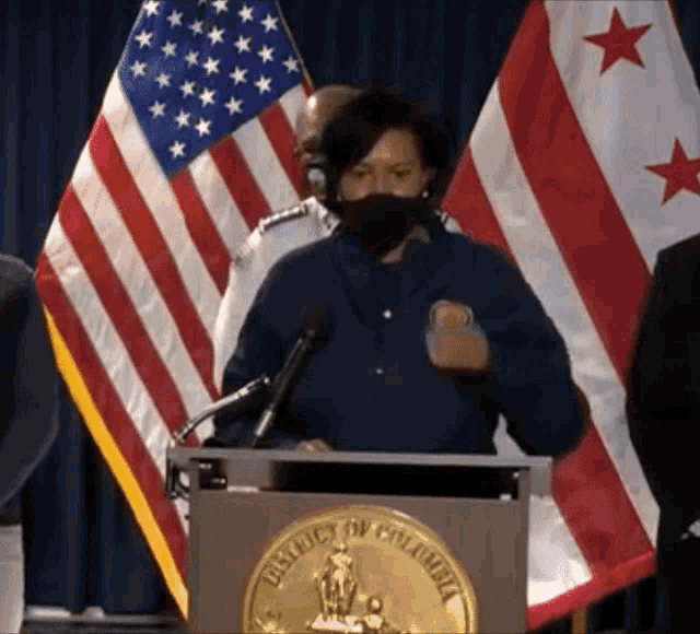 a woman stands at a podium with the district of columbia seal on it
