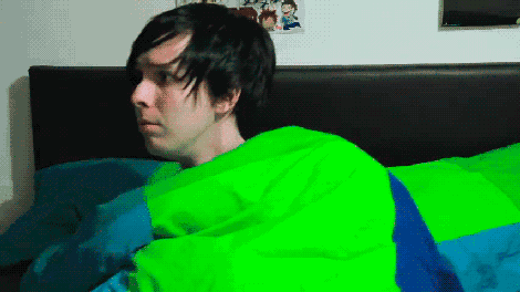 a man laying in bed with a green blanket