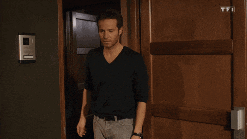 a man in a black shirt is standing in front of a door that says tft on it