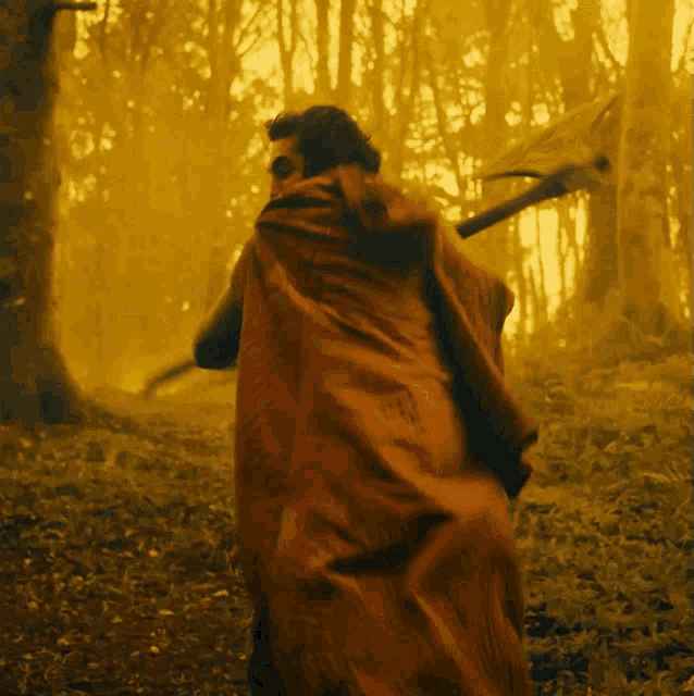a man in a red cape walking through a forest