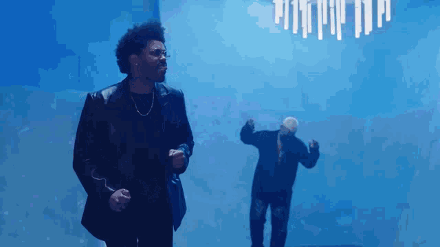 a man in a black jacket stands next to another man in a black jacket