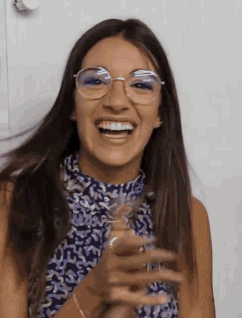a woman wearing glasses is laughing and clapping