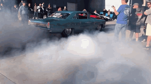 a man taking a picture of a car with smoke coming out of the wheels