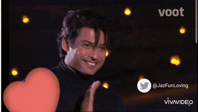 a man in a black shirt is smiling in front of a screen that says voot on it