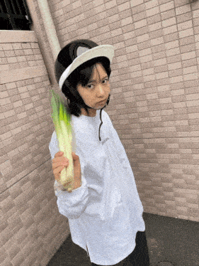 a young girl wearing a helmet and holding a green vegetable