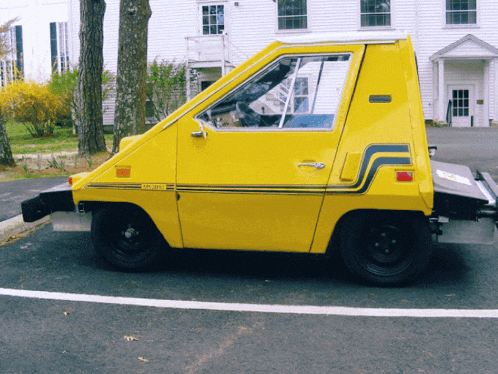 a small yellow car with a license plate that says ' jcr ' on it is parked on the side of the road