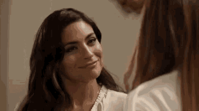 a couple of women are looking at each other and smiling .